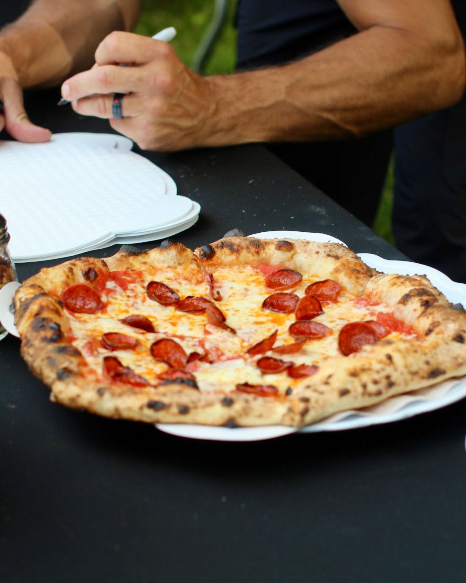 A sliced pepperoni pizza from Under Fire Pizza at a pop-up table
