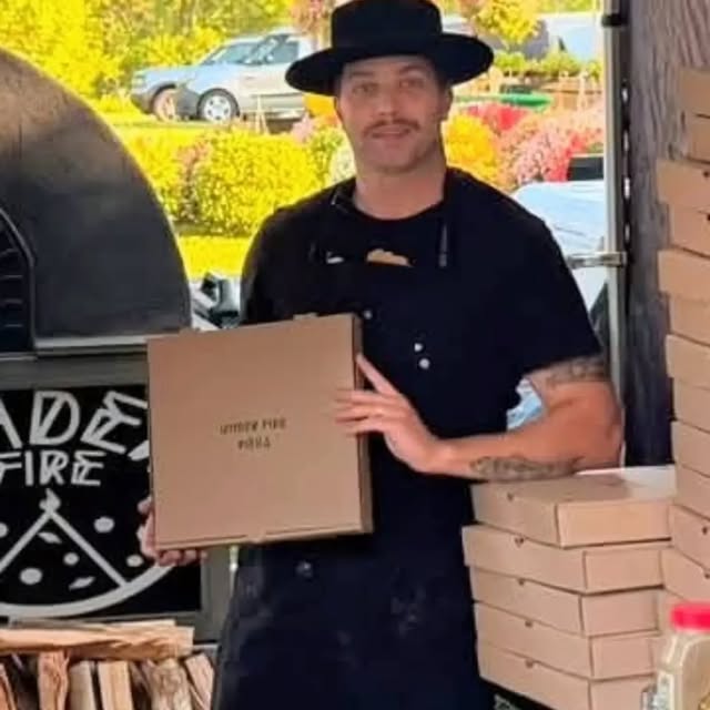 Under Fire Pizza catering with pizza boxes beside the mobile oven